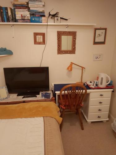 邓弗姆林Homely Haven, Dunfermline的一间卧室配有一张桌子、一台电脑和一把椅子