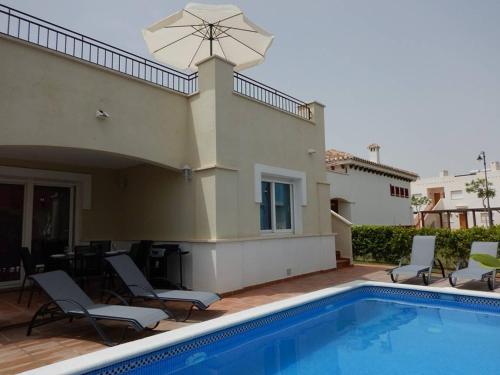 托雷帕切科2-bedroom Villa with pool的房屋旁的游泳池配有椅子和遮阳伞
