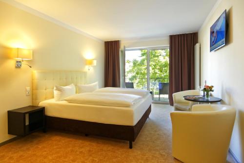 奥斯特西巴德钦诺维茨Hotel am Kurpark的配有一张床和一把椅子的酒店客房