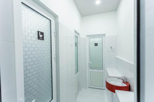 撒马尔罕Registan Hostel的白色的浴室设有红色水槽和淋浴。