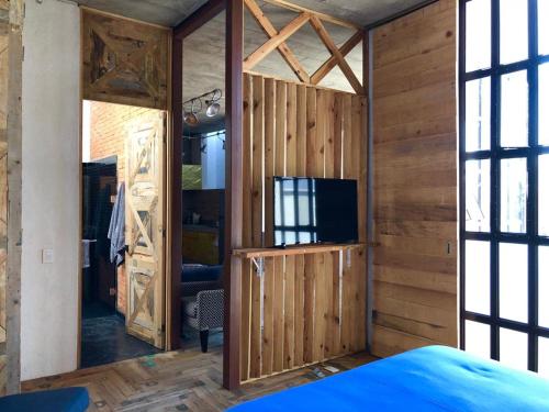 圣米格尔-德阿连德Canela Fina - Adults Only的一间带木墙和电视的房间和一间卧室