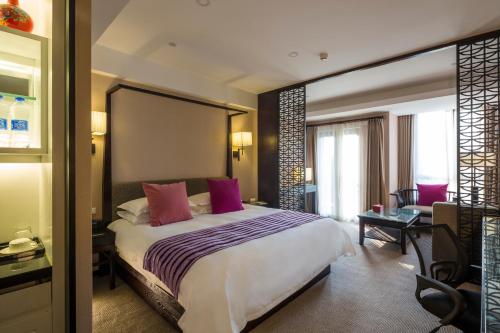杭州杭州西溪谷君亭酒店的卧室配有一张带粉红色枕头的大床