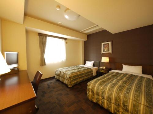 饭田市埃达路特酒店的酒店客房设有两张床、一张书桌和一个窗户。