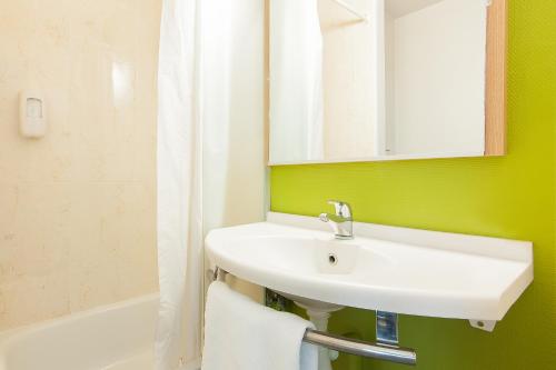 布吕热B&B HOTEL Bordeaux Lac sur Bruges的浴室配有盥洗盆、镜子和浴缸