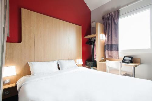 布吕热B&B HOTEL Bordeaux Lac sur Bruges的卧室配有白色的床和红色的墙壁