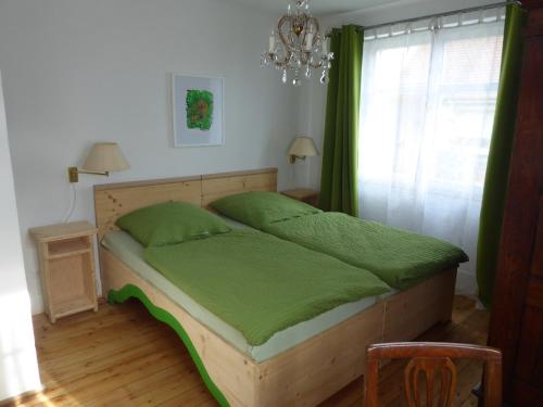 莱茵河畔威尔Pension Zur Rose的一间卧室配有一张带绿色床单和吊灯的床。