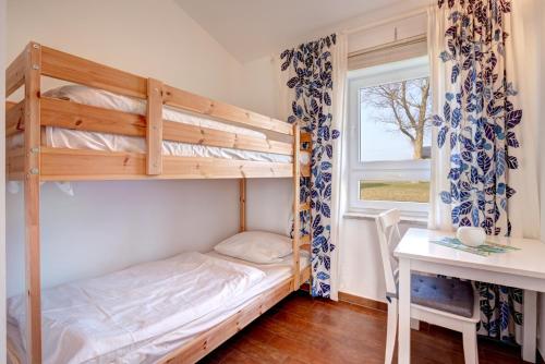 阿尔滕基兴Knaus Camping- und Ferienhauspark Rügen的一间卧室配有双层床、书桌和窗户。