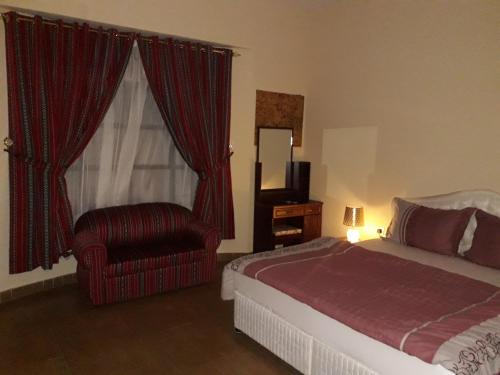 海塞卜Ahlam Musandam Villa的卧室配有床、椅子和窗户。