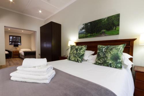 约翰内斯堡The Pecan Tree Guesthouse的卧室配有白色床和毛巾