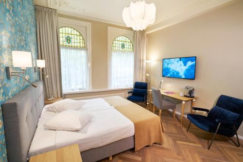 鹿特丹范瓦尔苏姆酒店的酒店客房,配有一张床、一张桌子和椅子