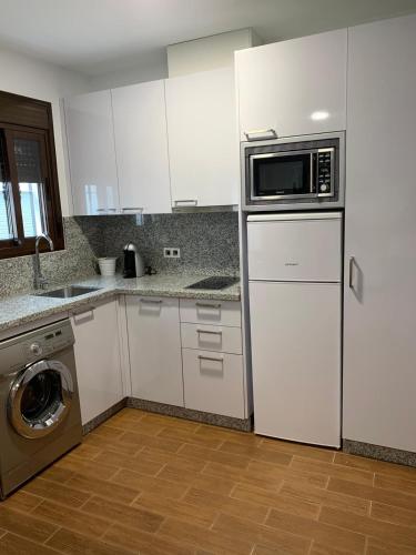 科因Estudio Luna的厨房配有白色橱柜、微波炉和洗碗机。