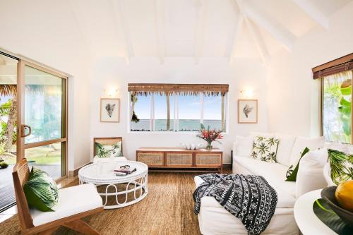 拉罗汤加Motu Beachfront Art Villas的客厅配有白色家具和大窗户