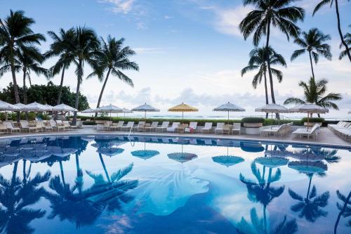 檀香山哈利库拉尼酒店的一座棕榈树和遮阳伞的游泳池