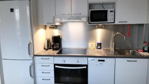 图尔库Sunshine Apartment的厨房配有白色橱柜、水槽和微波炉