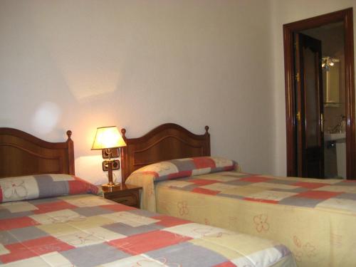马德里洛斯安第斯旅馆的一间卧室设有两张床和一张桌子上的台灯。
