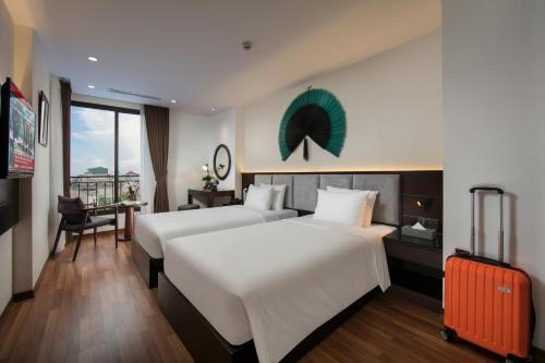 河内Hanoi Fiesta Hotel & Spa的酒店客房带两张床和行李箱