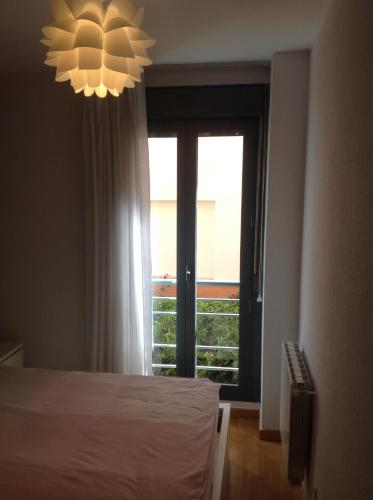 马德里Nice stay的一间卧室设有一张床、一个窗户和一个吊灯。