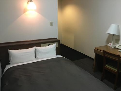 松本Garden Hotel Matsumoto的酒店客房配有一张床和一张带台灯的书桌