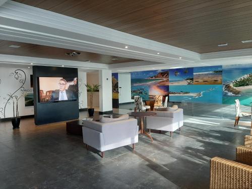 若昂佩索阿布兰科公寓式酒店的客厅配有白色家具和大屏幕电视