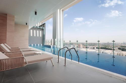 迪拜Millennium Executive Apartments Mont Rose的一个带长椅和大窗户的游泳池