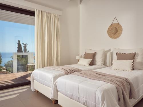 圣尼古拉奥斯PanoPlagia Villa的白色卧室设有两张床和大窗户