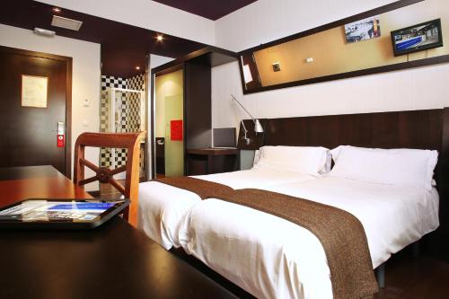 马德里格兰大街阿文尼达酒店的酒店客房配有一张床、一张书桌和一台笔记本电脑