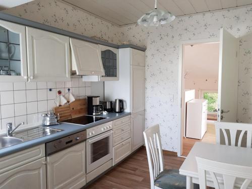 奥尔登堡Gartenblick的厨房配有白色橱柜、水槽和桌子