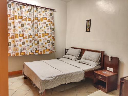 蒙巴萨Marigold Guest House的一间卧室配有床、窗帘和床罩。