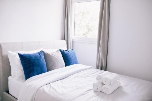 伦敦Authentic Battersea Experience的一张带蓝色枕头的白色床和毛巾