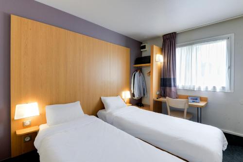 布格奈斯B&B HOTEL Nantes Aéroport的酒店客房设有两张床、一张书桌和一个窗户。