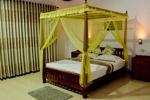 代尼耶耶Rainforest Lodge, Deniyaya的一间卧室配有一张带黄色窗帘的天蓬床