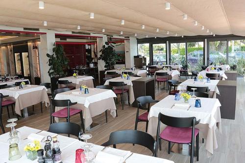 西尔米奥奈奥罗拉酒店的餐厅配有桌椅和白色的桌椅