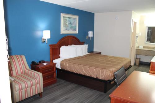 塔斯卡卢萨Americas Best Value Inn Tuscaloosa的配有一张床和一把椅子的酒店客房