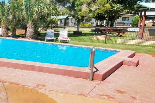 土乌巴图文巴BIG4城市花园度假酒店的庭院内的游泳池,配有桌椅