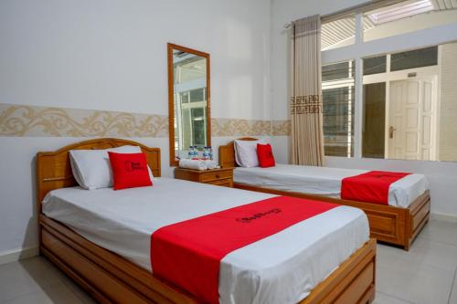 帕卢RedDoorz Plus Syariah at Alam Raya Hotel的一间卧室配有两张红色和白色床单
