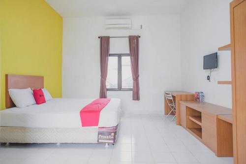 占碑市RedDoorz Syariah @ Pasir Putih Jambi的一间卧室配有一张床、一个窗口和一张书桌
