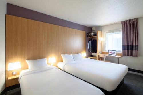 热姆诺B&B HOTEL Aubagne Gémenos的酒店客房设有两张床和窗户。