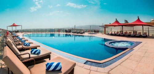 马斯喀特City Seasons Hotel & Suites Muscat的度假村内带躺椅的大型游泳池