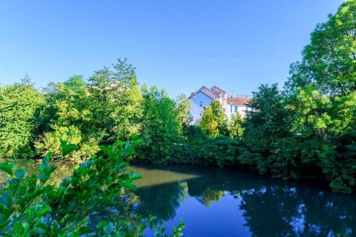 斯特拉斯堡Hotel Strasbourg - Montagne Verte & Restaurant Louisiane的一条有树木的河流和一座房子