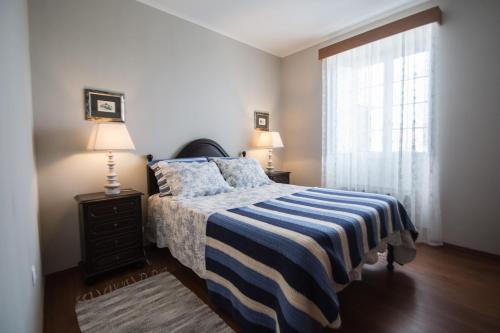 波尔图镇Casa da Avó - Vila do Porto的一间卧室配有一张带条纹毯子的床和窗户