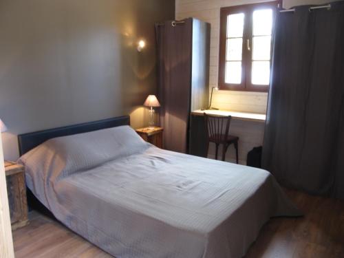勒帕莱La Saline的一间卧室配有一张床、一个窗口和一张书桌