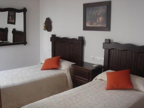 蒙托罗卡萨迈卡酒店的卧室内的两张床和橙色枕头