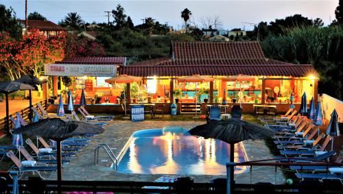 圣乔治斯Stars Hotel的餐厅前的游泳池配有椅子和遮阳伞