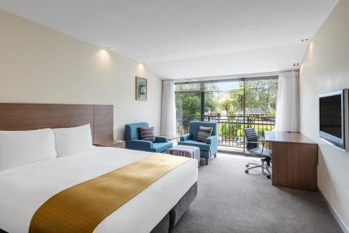 奥克兰奥克兰机场智选假日酒店的酒店客房带一张床、椅子和电视