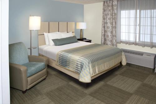 韦科Candlewood Suites Waco, an IHG Hotel的一间卧室配有一张床和一把椅子