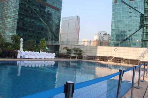 深圳深圳皇庭V酒店的一座带白色椅子的大型游泳池,