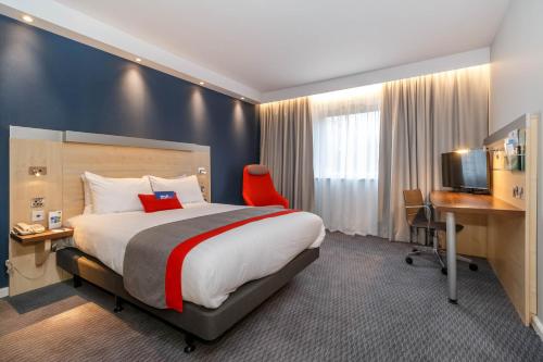 沃尔索尔快捷假日沃尔萨尔M6高速公路10号岔口酒店的酒店客房设有一张大床和一张书桌。
