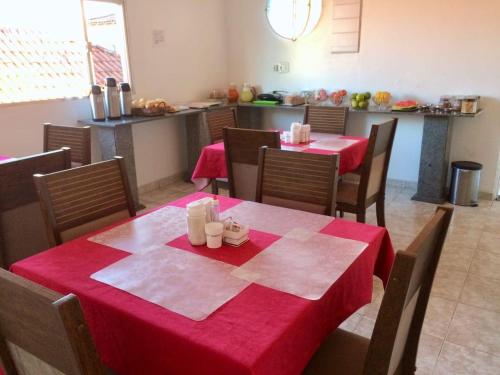 坎普斯戈伊塔卡济斯Pousada Pinheiro的一间用餐室,配有两张桌子和椅子,配有红色桌布