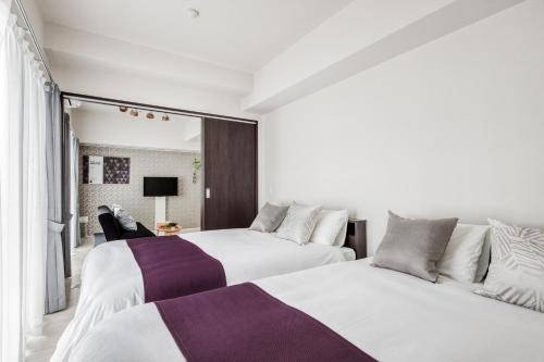 大阪BON Condominium Umeda的白色和紫色客房的两张床