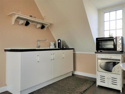 韦茨拉尔斯皮尔伯格公寓的厨房配有白色橱柜、水槽和微波炉